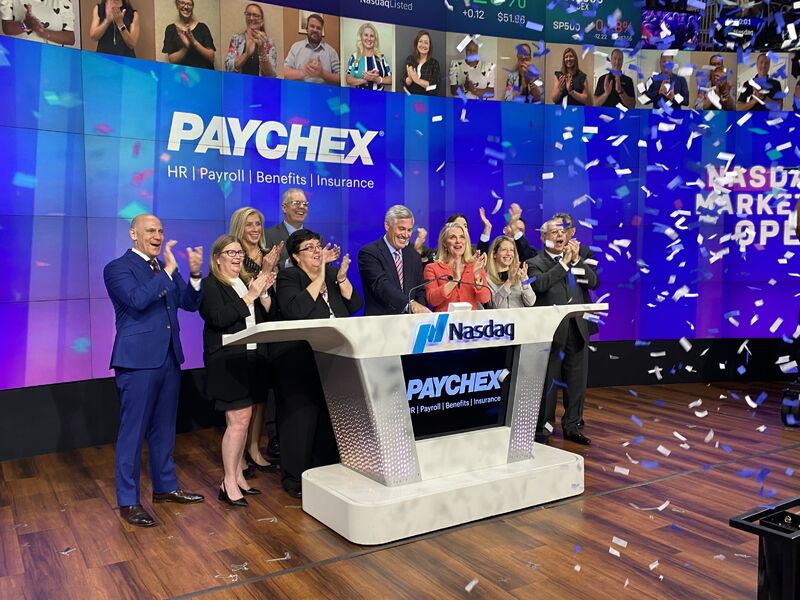 John Gibson at the center of the Nasdaq podium with Paychex colleagues applauding beneath falling confetti