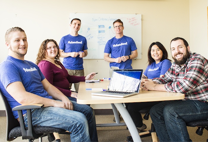 Automational team members gathered around a meeting table with a laptop and whiteboard