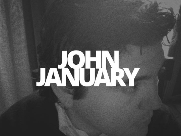 A monochrome interview portrait of John January in profile, overlaid with his name