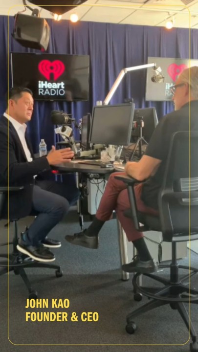 John Kao, left, speaking with Paul Corvino across microphones in an iHeartRadio studio