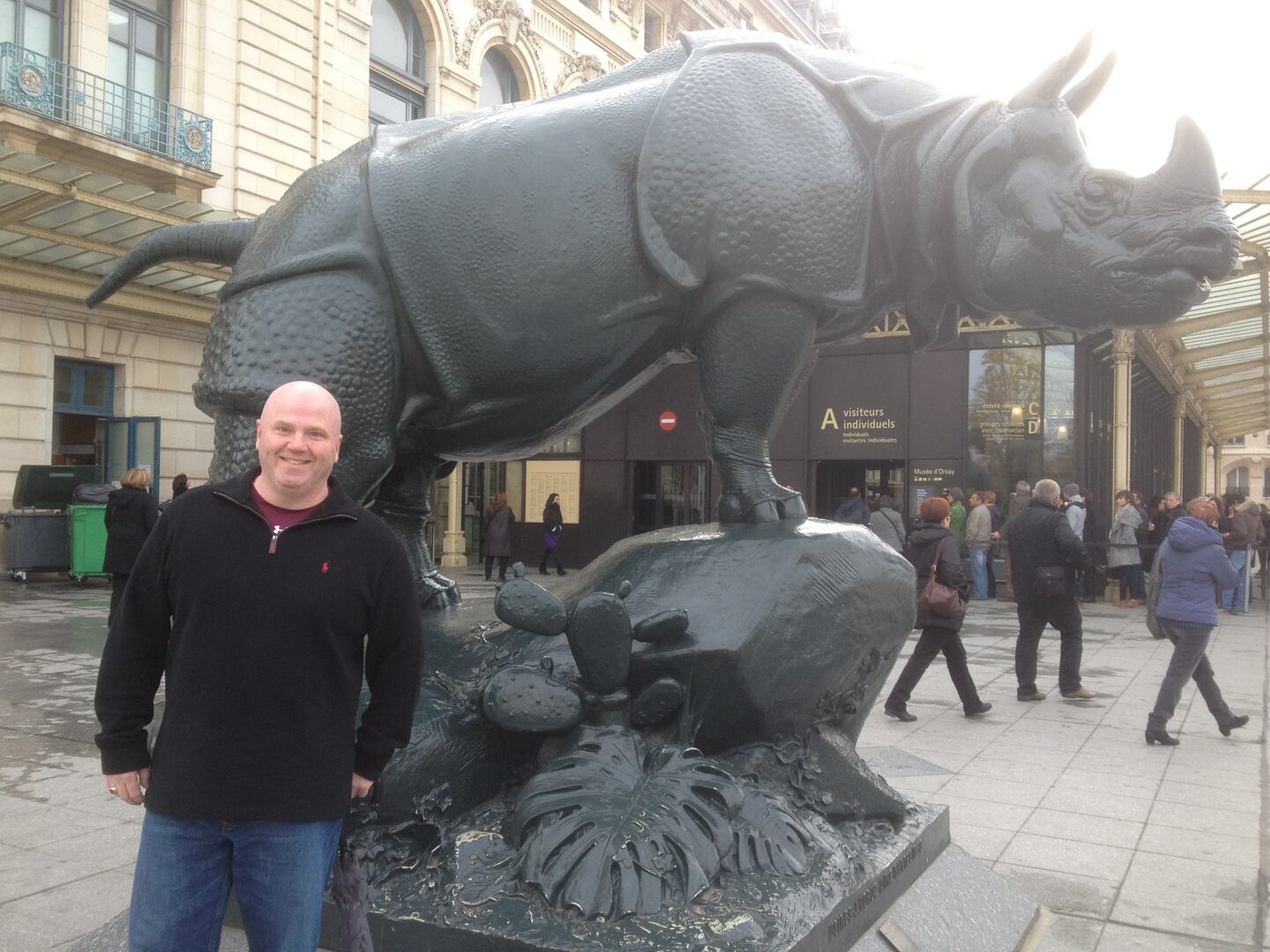 John Maguire standing beside a rhinoceros sculpture outside the Musée d'Orsay in Paris