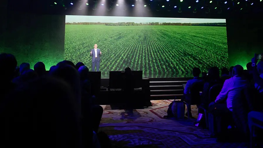 John May on the CES 2023 stage, with a field of crops on the screen behind him