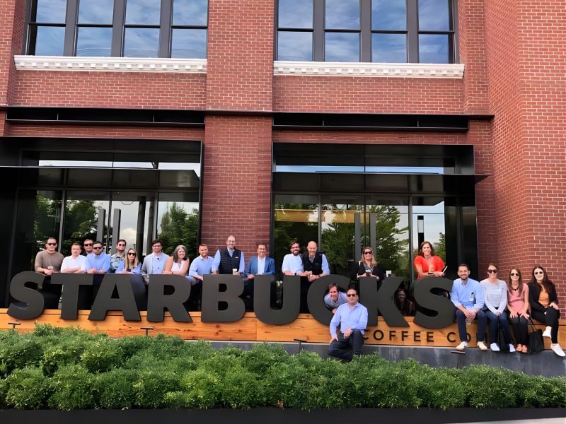 Monument colleagues gathered around a large Starbucks sign