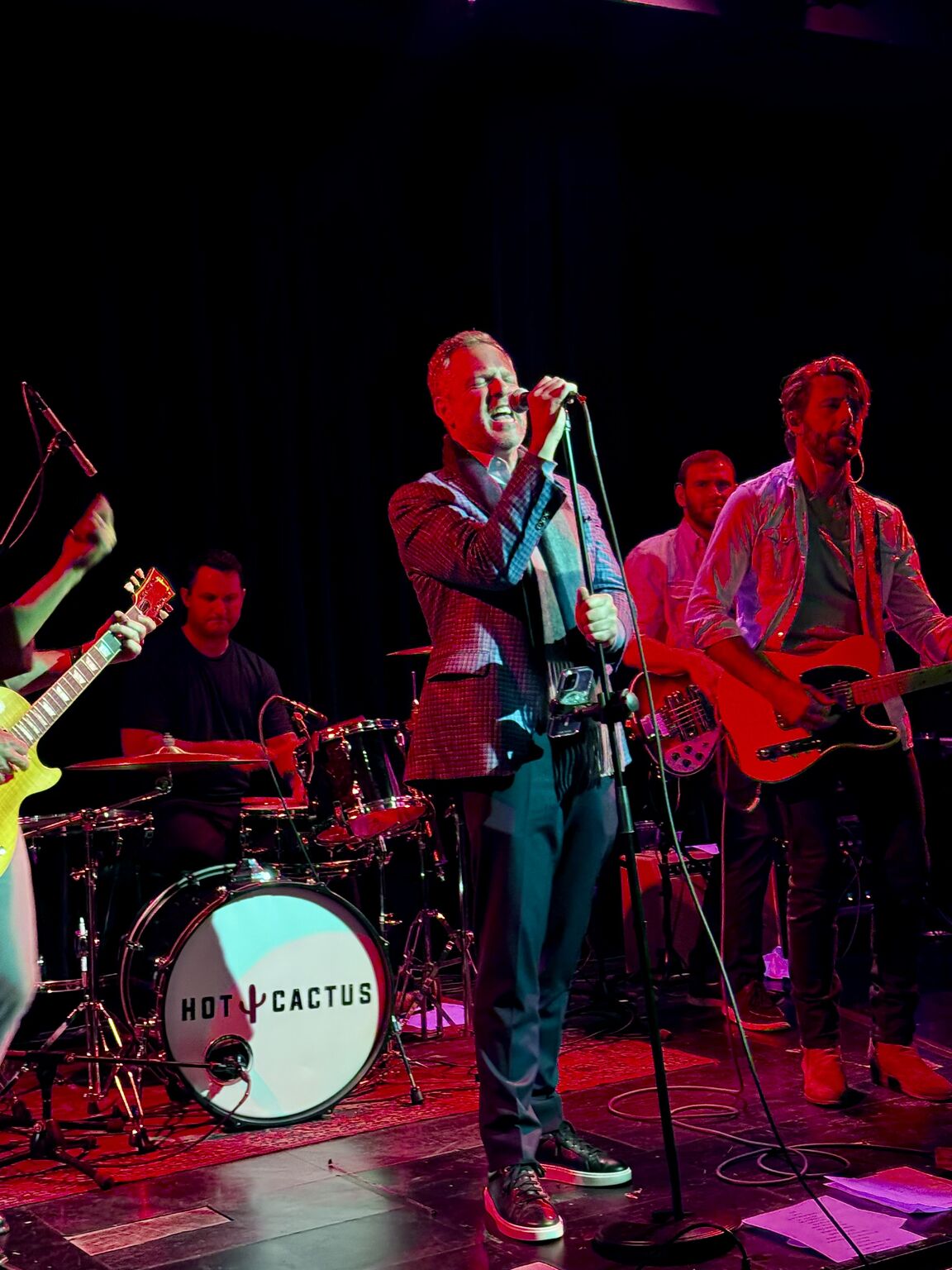 John Murray holding a microphone onstage with a live band