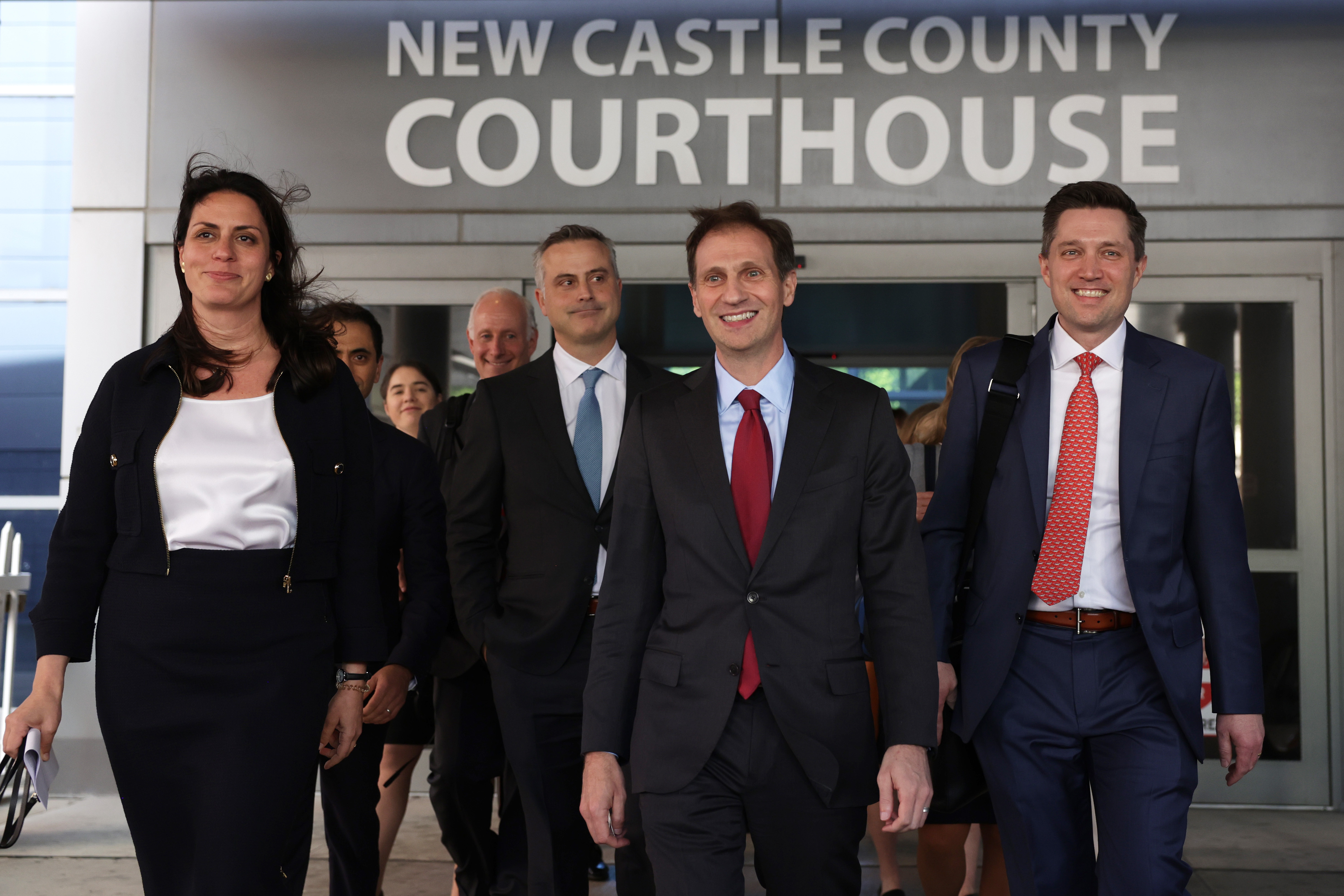 John Poulos, in a light blue tie, leaves the Delaware courthouse with Dominion's legal team on April 18, 2023.