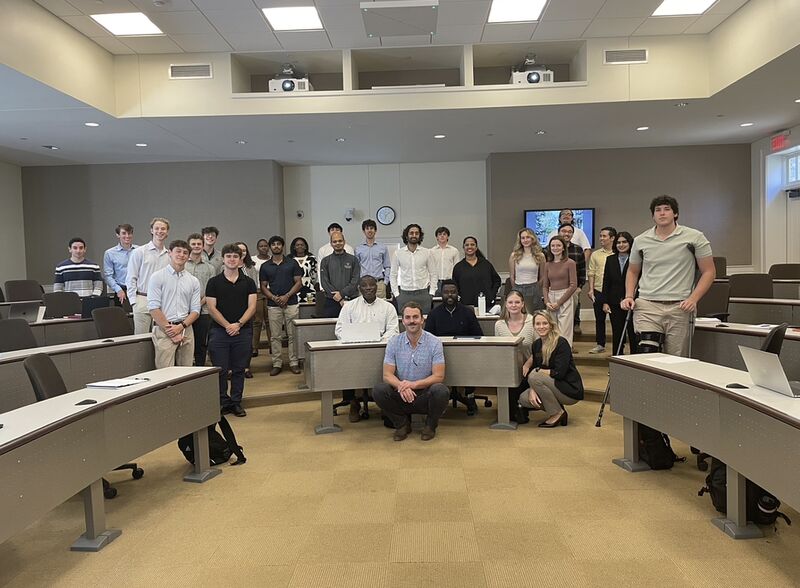 John Ribble seated at the front of a group photograph with Finance Academy attendees