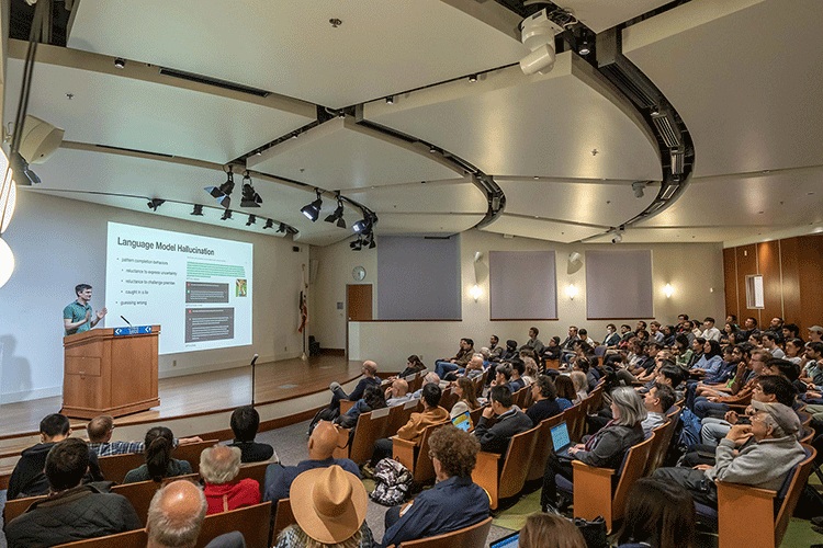 John Schulman speaking at a lectern during a UC Berkeley event