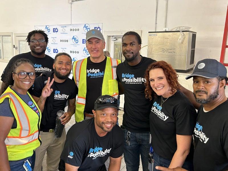 John Stankey, wearing a cap and reflective vest, with a group in Bridge to Possibility shirts.