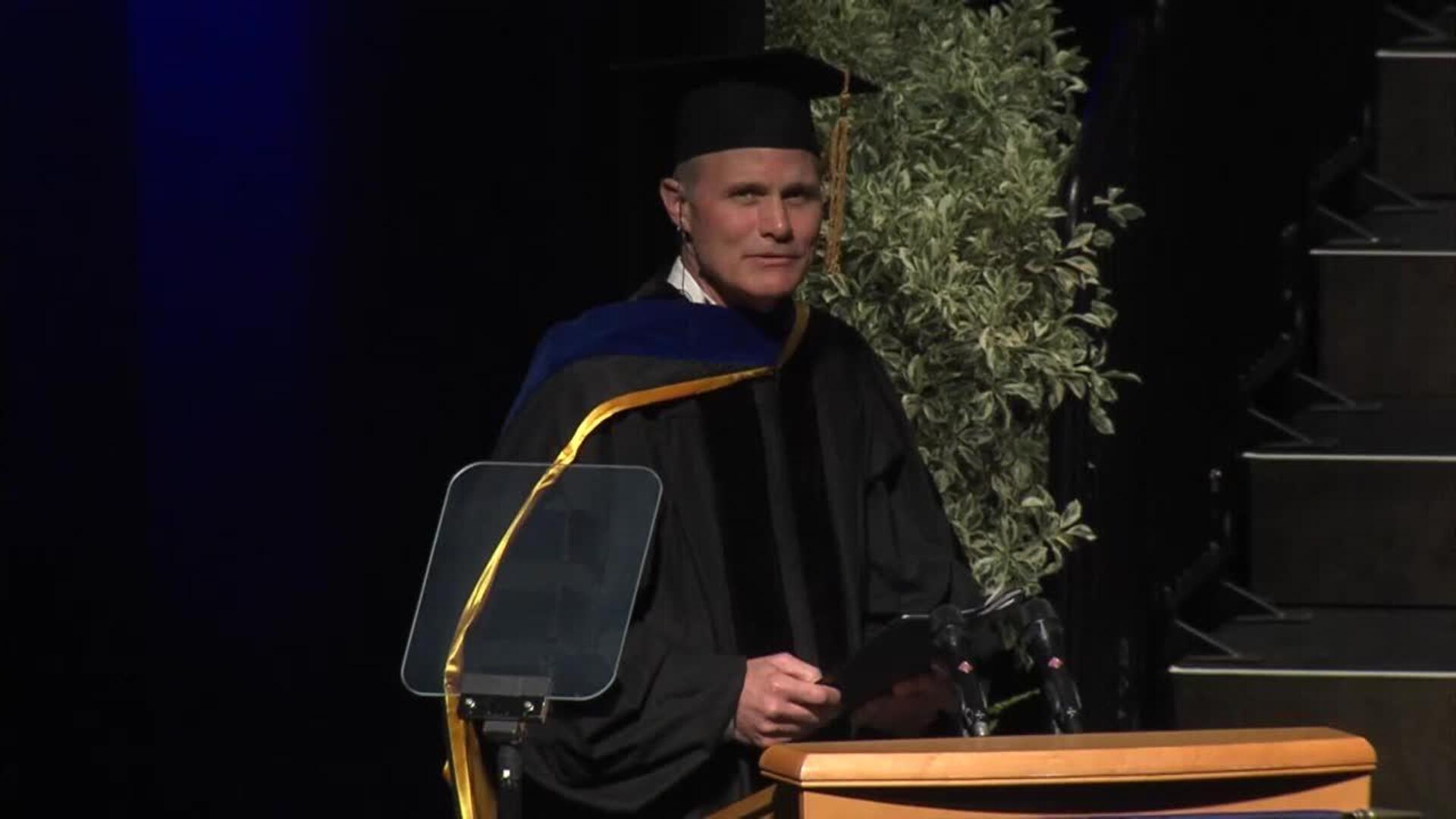 John Stuelpnagel at the lectern in academic regalia during the 2016 UC Davis commencement