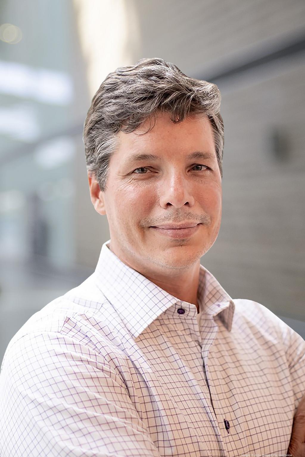 John Swigart in an office, wearing a light checked shirt