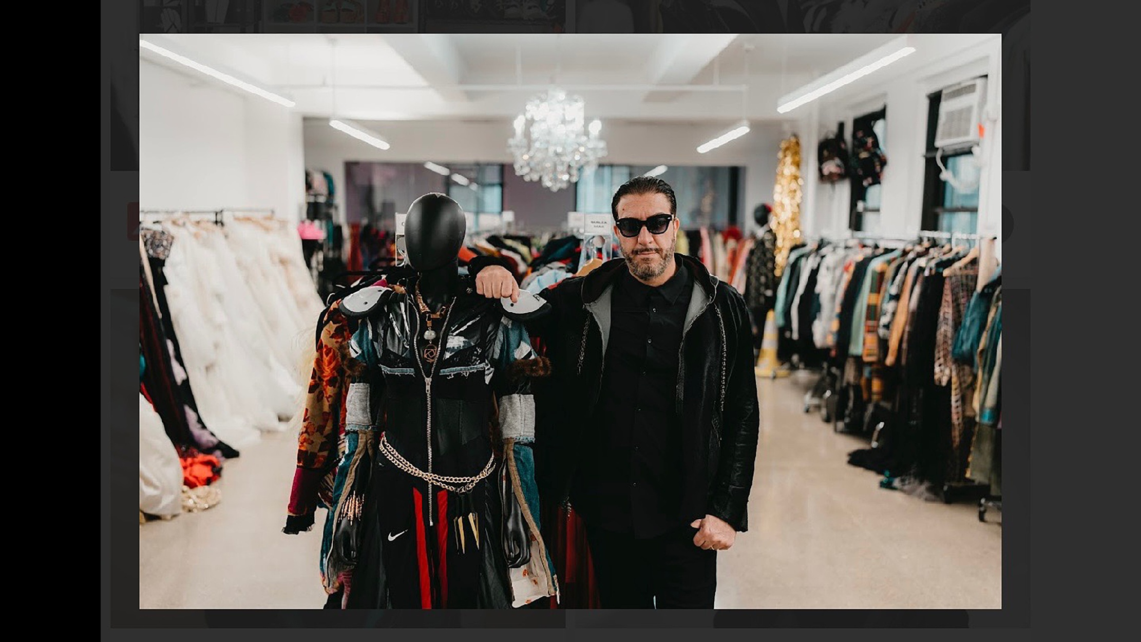 Johnny Cohen beside a dressed mannequin among the clothing racks at The Confessional Showroom