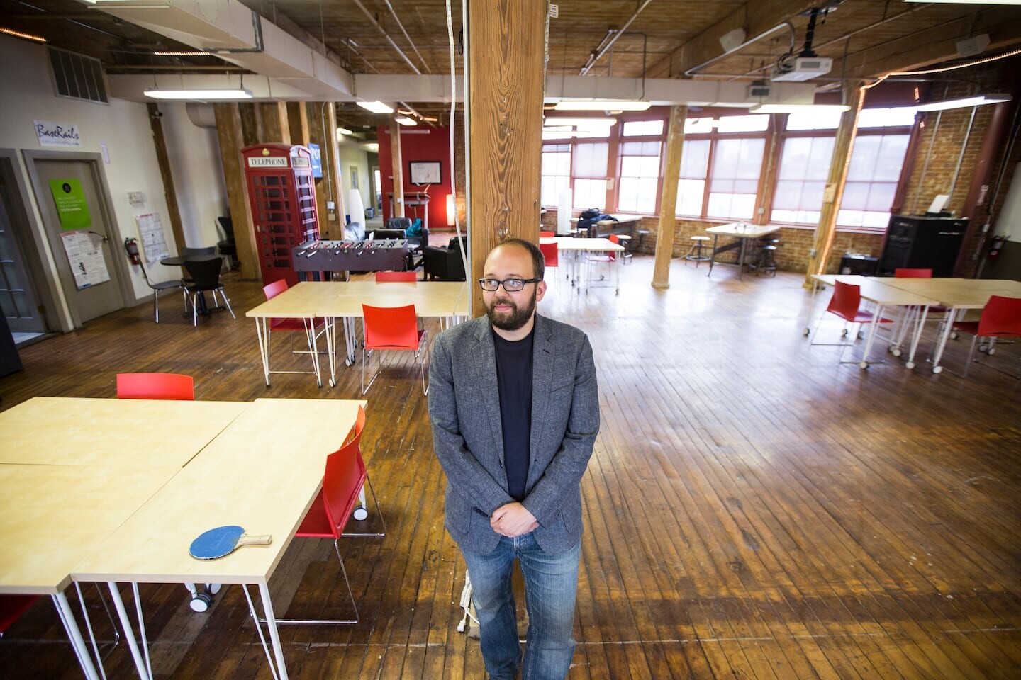 Jonathan Bittner standing in a bright Providence workspace with wood floors and shared tables