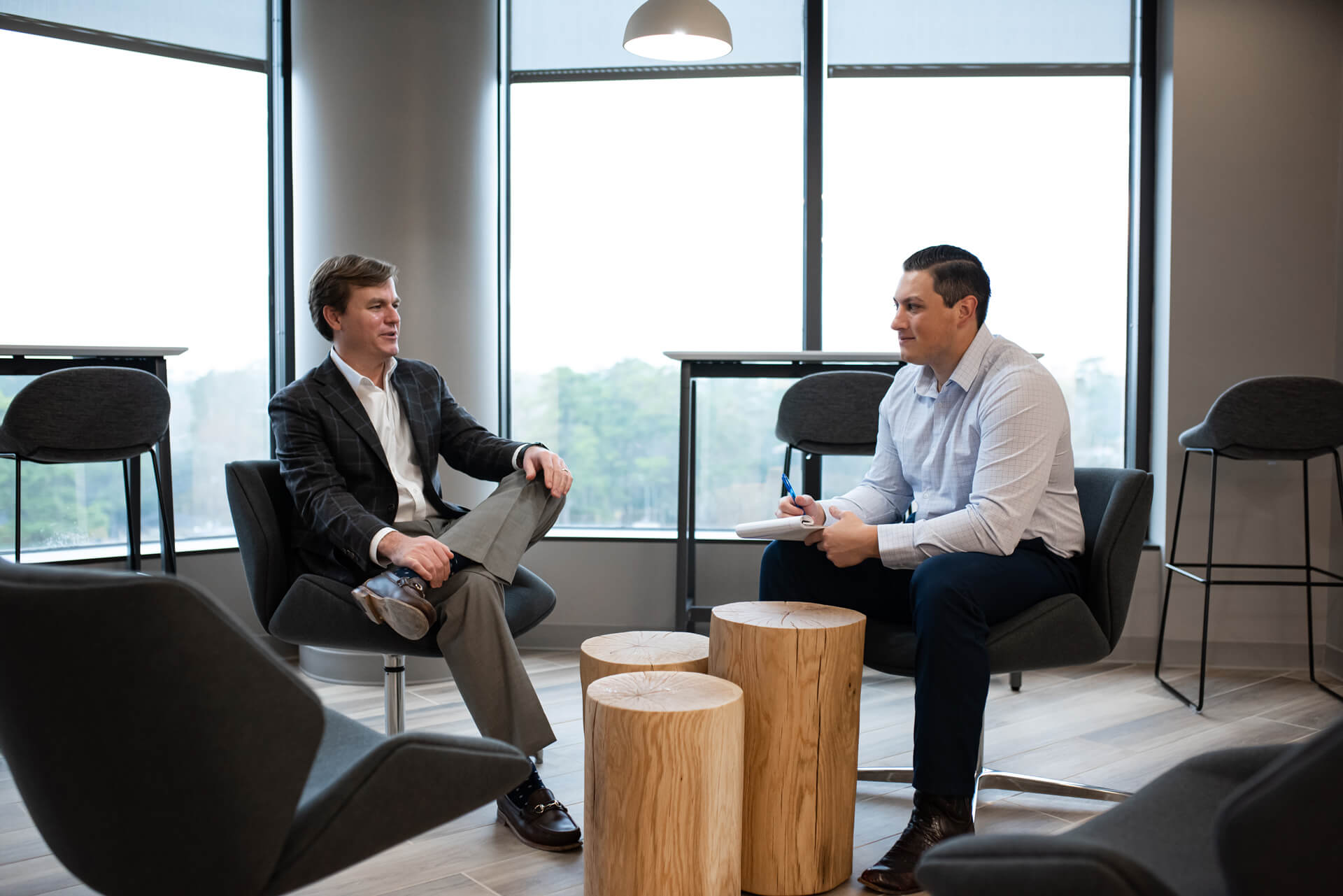 Two colleagues talking in a Jones Capital office, with a notebook and timber side tables