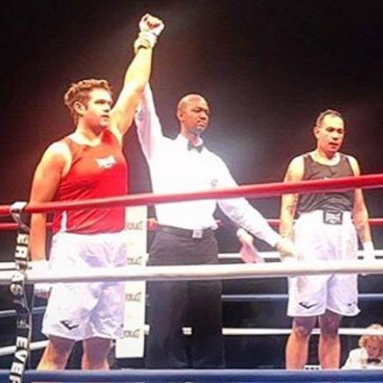 Jonathan Halvorson in red boxing gear as a referee raises his hand after an amateur bout
