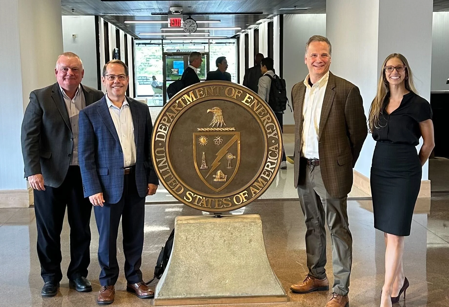 Tom Dorsch, Don Simoneau, Jonathan Strimling and Alexandra Harris beside the Department of Energy seal