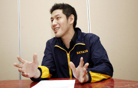 Jonathan Sudharta speaking at a table in a navy and yellow Batavia jacket