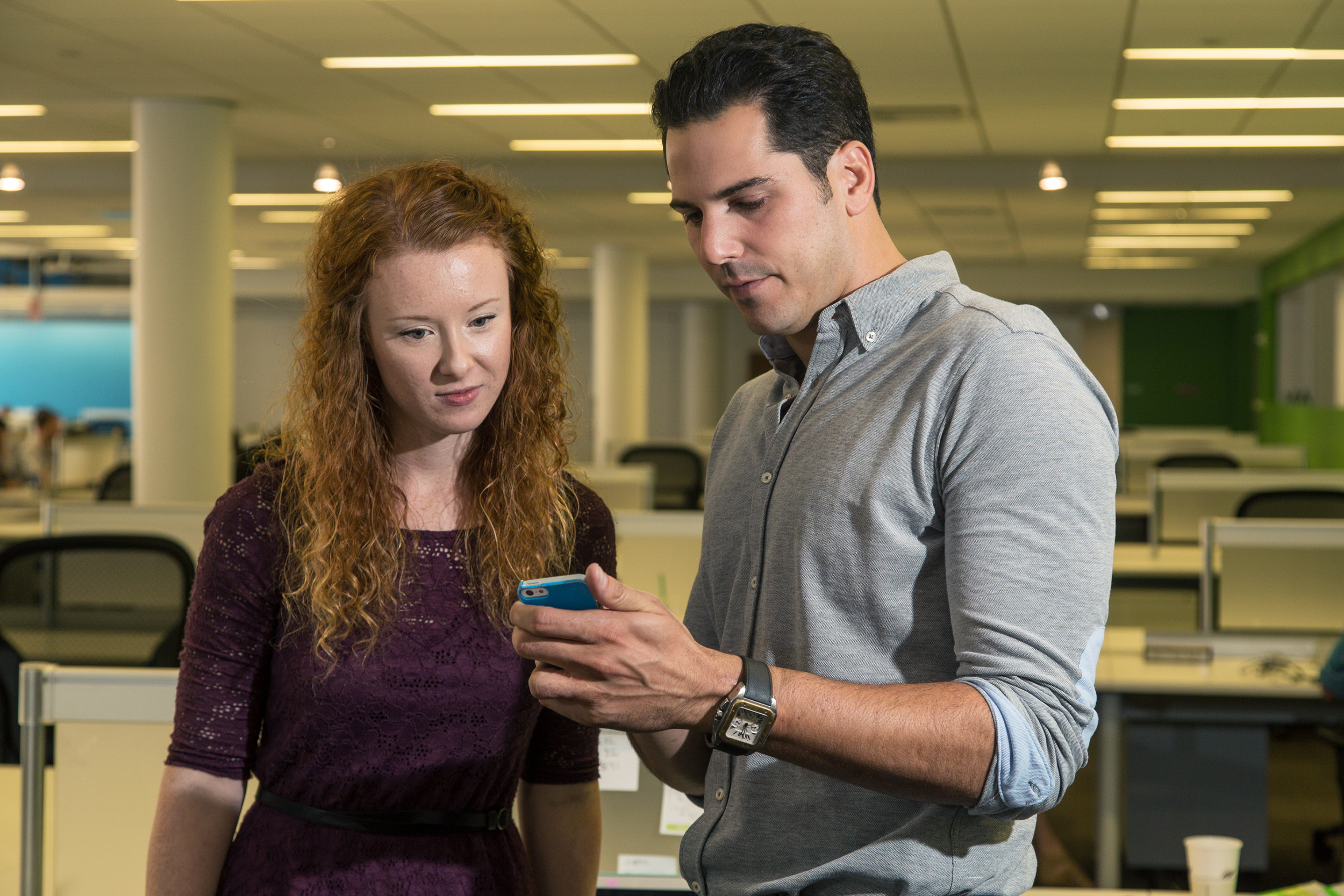 Jonathon Ende and a colleague looking at a phone in the SeamlessDocs office