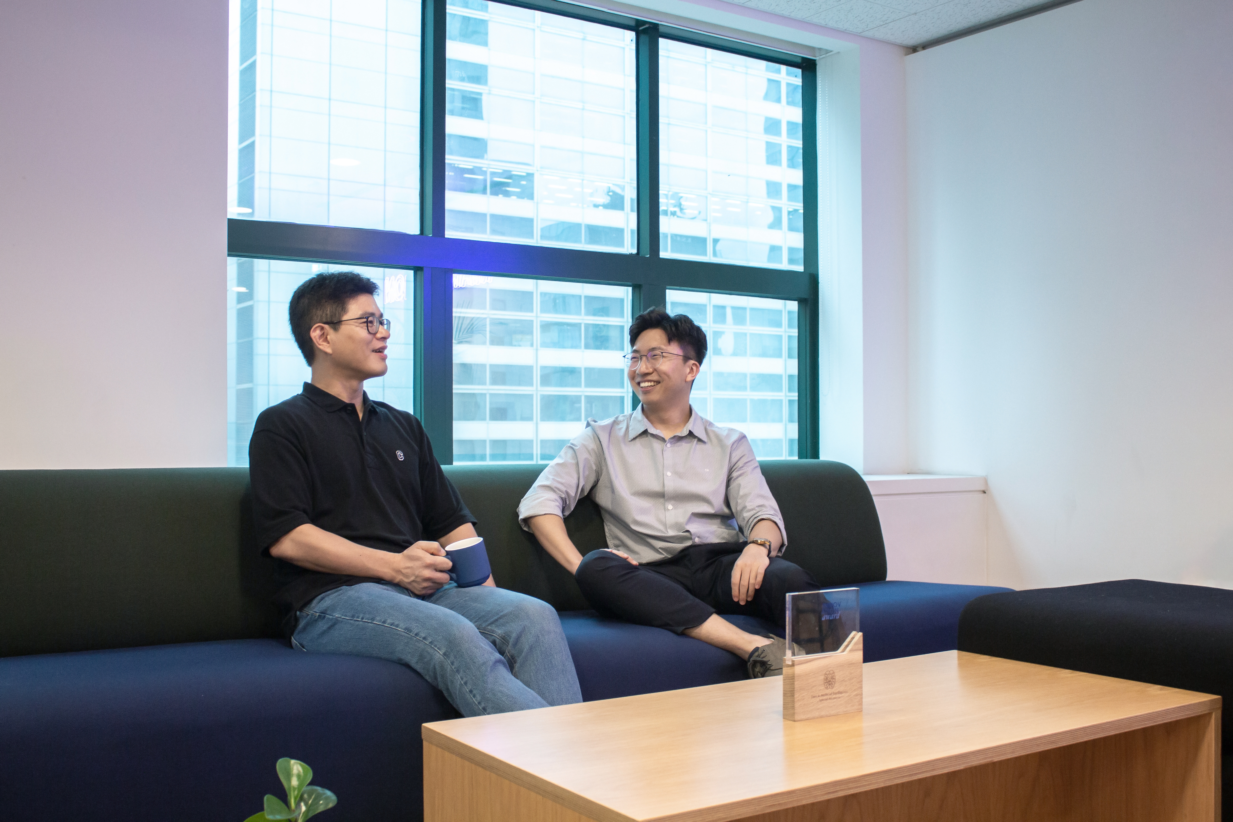 Joon Kim and MarqVision engineering leader SeungHyun Lim in conversation on an office sofa