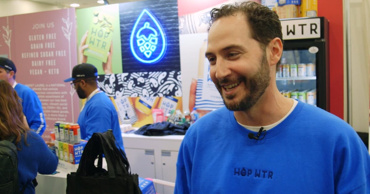 Jordan Bass speaking at the HOPWTR booth during a trade event