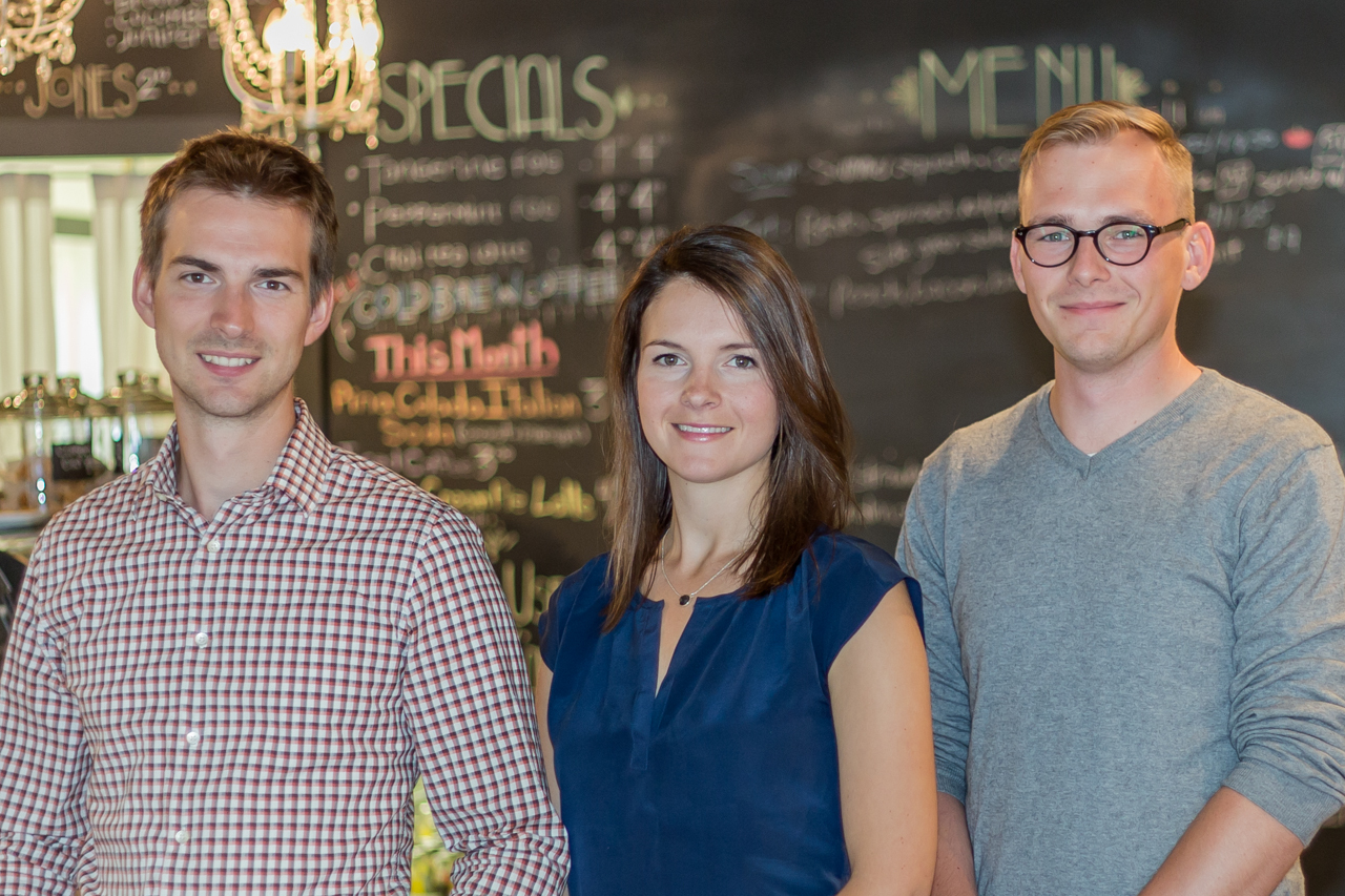 Three 7shifts founders standing together in front of a restaurant chalkboard menu