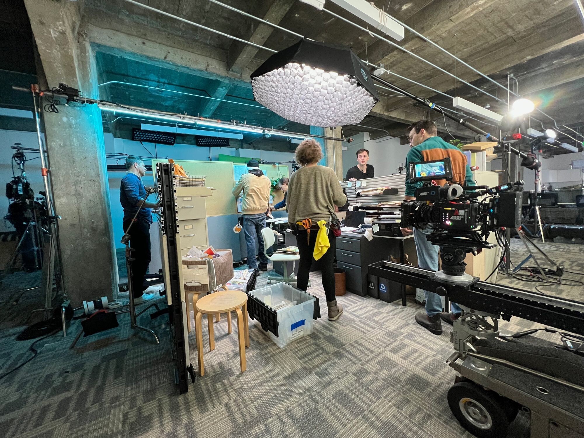 A film crew builds a practical insurance-office set at Comulate