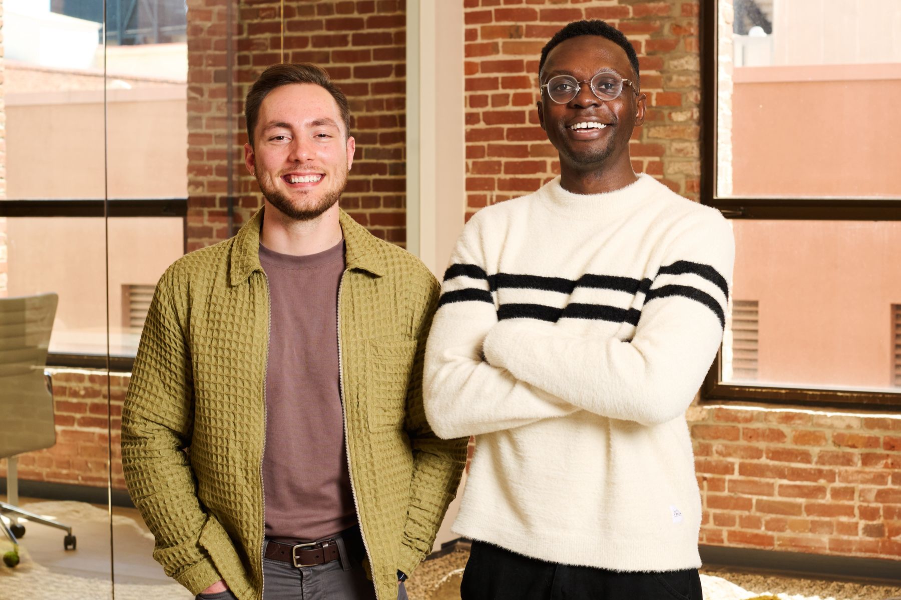 Vizcom co-founders Jordan Taylor and Kaelan Richards standing together in a bright brick-walled workspace