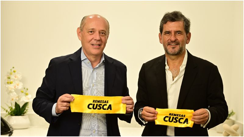 Jorge Raull, left, and Gustavo Ruiz holding yellow Remesas Cusca ribbons at the company's tenth-anniversary celebration