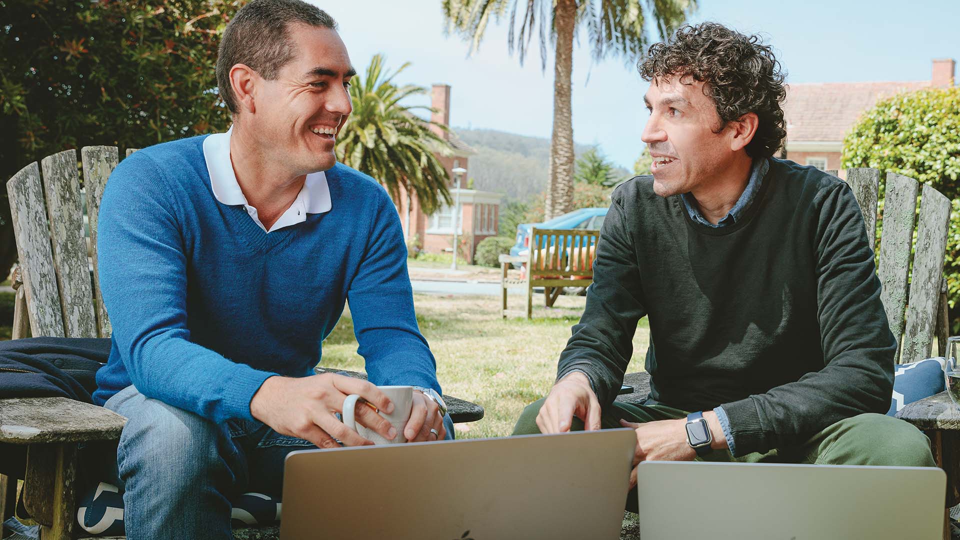 José M. Mejía Oneto, left, and Sebastian Sanchez de Lozada, right, talking outdoors with laptops