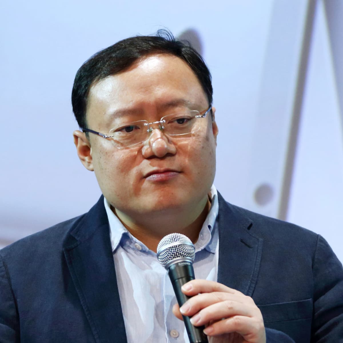 Joseph Chen speaking with a handheld microphone at a technology conference