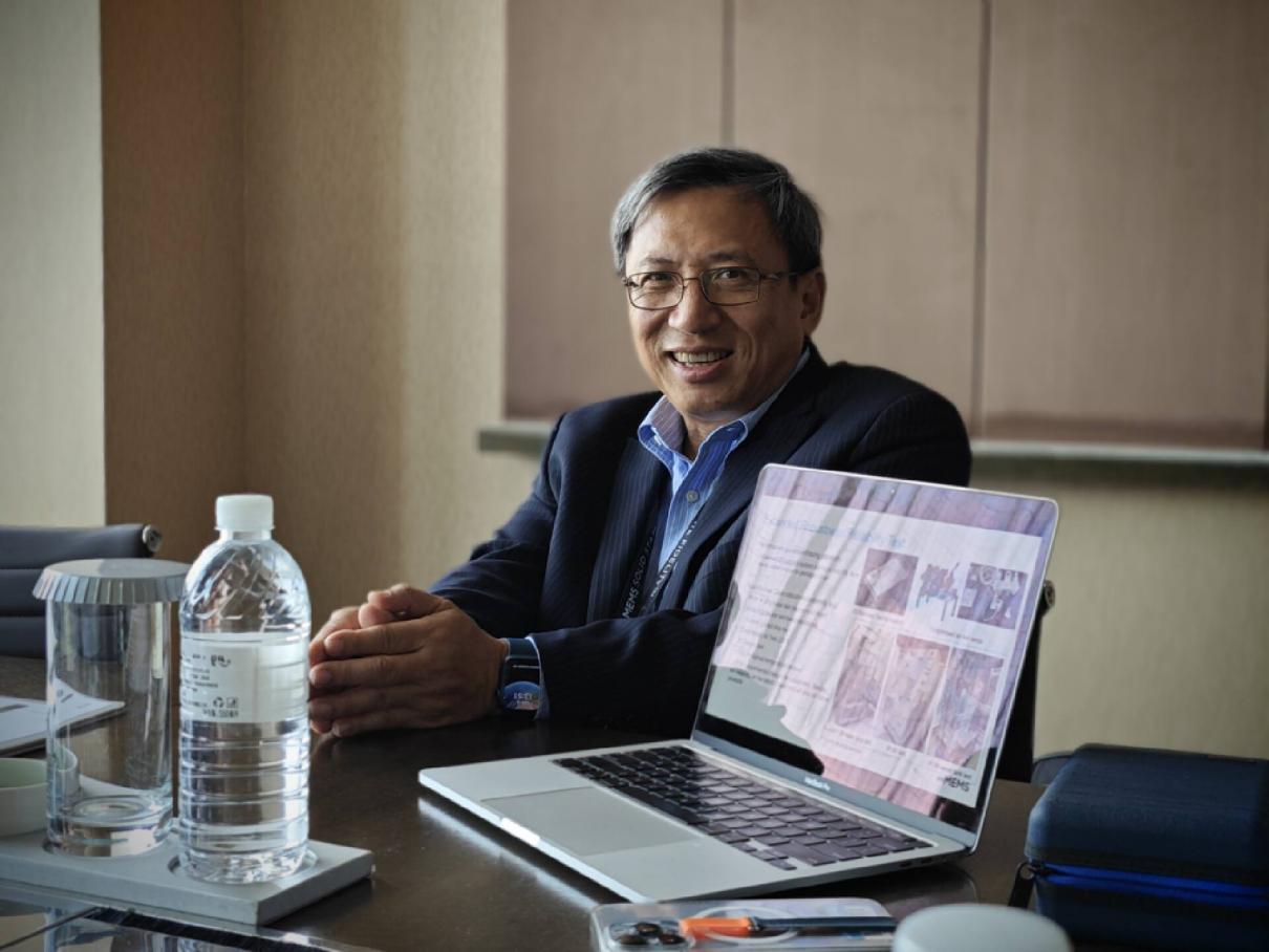 Joseph Jiang seated at a table during an interview, with a laptop open beside him