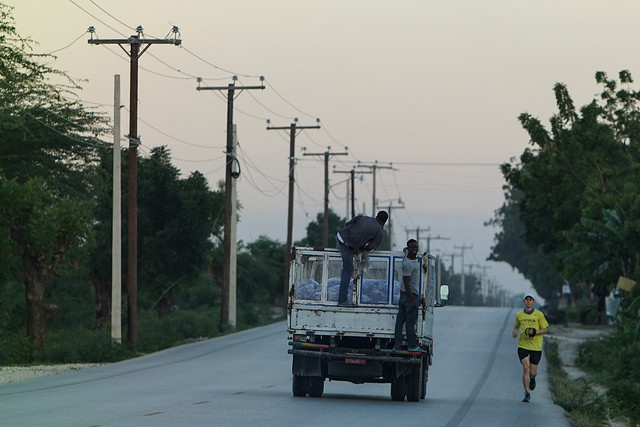 Josh Elkes runs along a road beside a truck during the 2015 Run Across Haiti.