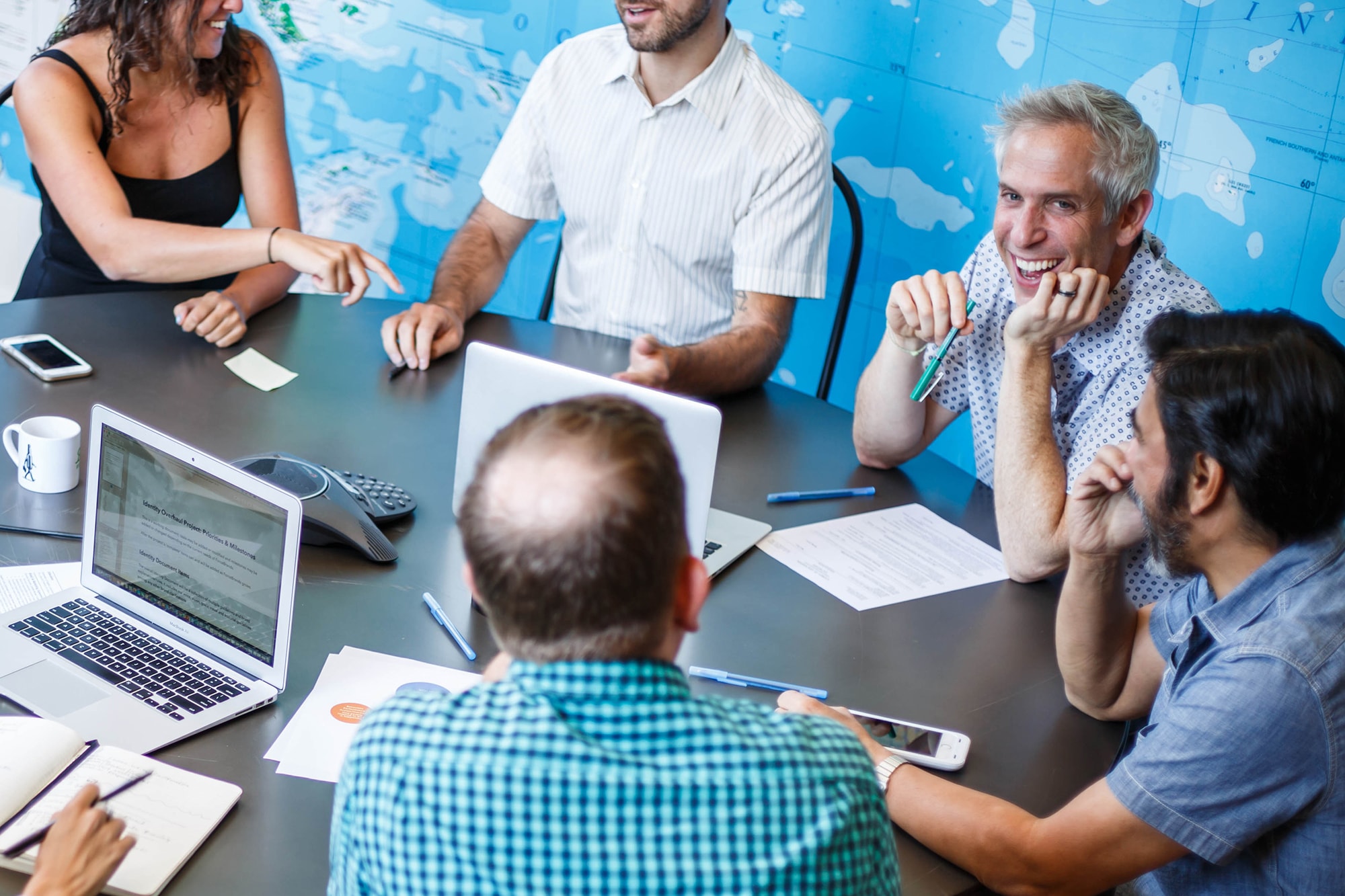 Josh Wand, at right, smiles while leading a meeting with ForceBrands colleagues around a conference table.