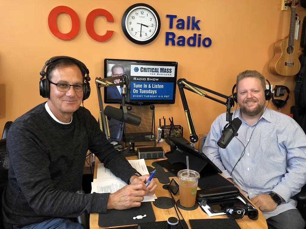 Josh Wilhelm, right, wearing headphones at a microphone in the OC Talk Radio studio