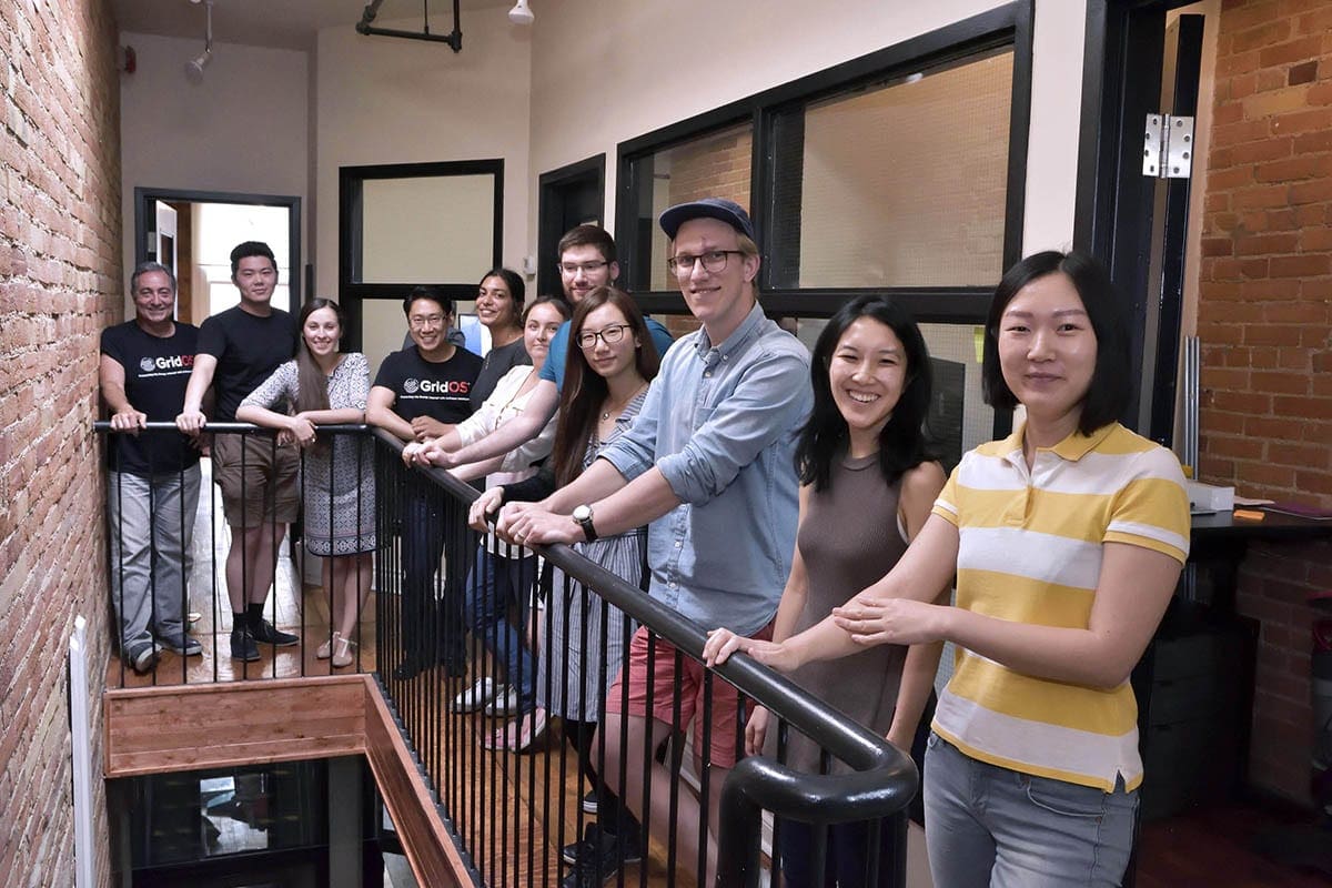 The Opus One Solutions team gathered around a stairwell railing in its brick-walled office