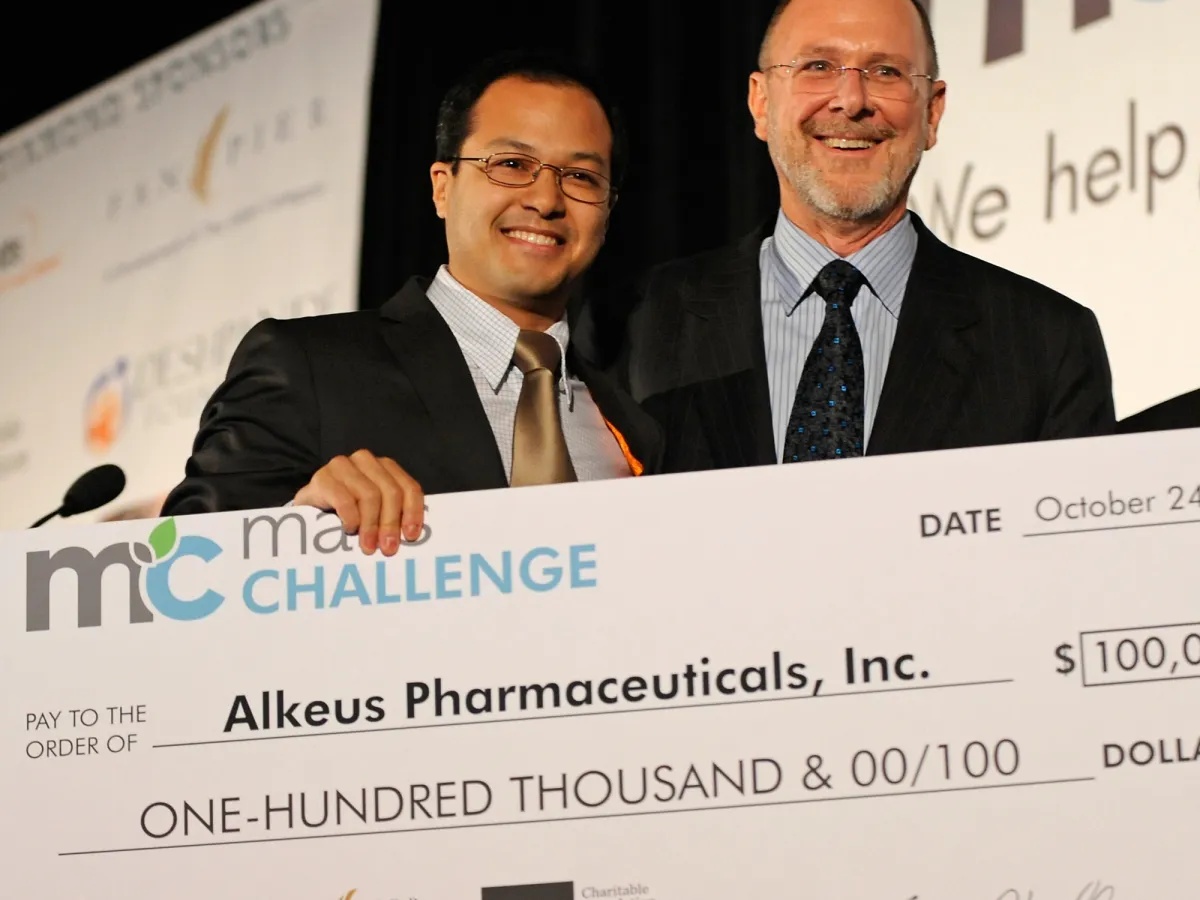Leonide Saad and Joshua Boger smiling behind a ceremonial MassChallenge award check