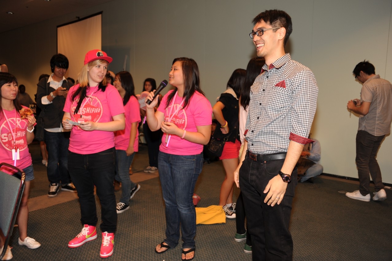 Joshua Lau smiling beside attendees at an SMTown fan meetup in Los Angeles
