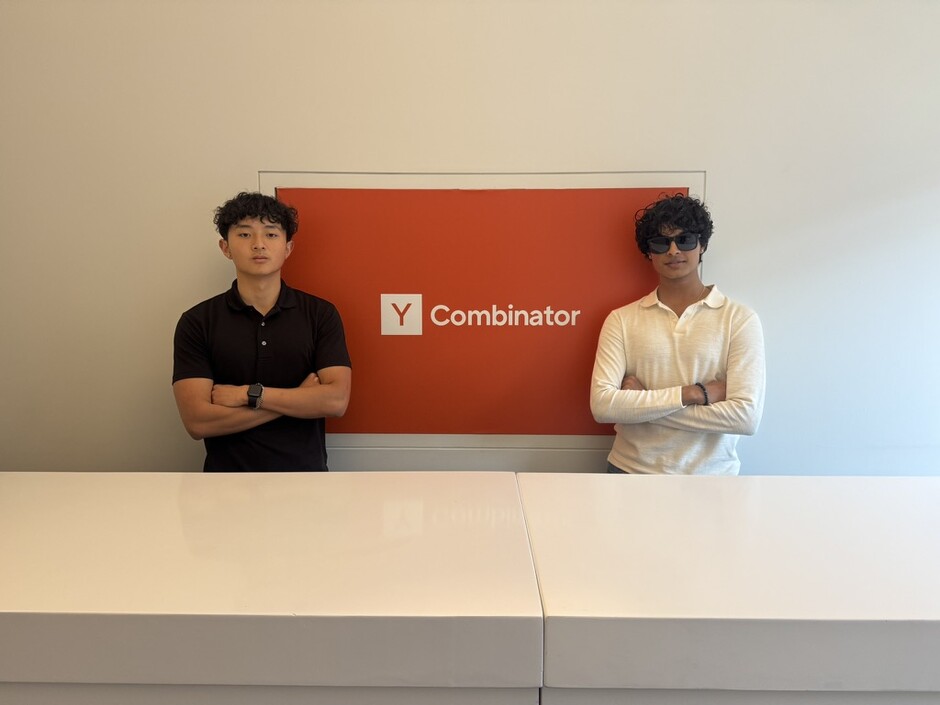 Joshua Wang and Sanmay Sarada standing on either side of a Y Combinator sign