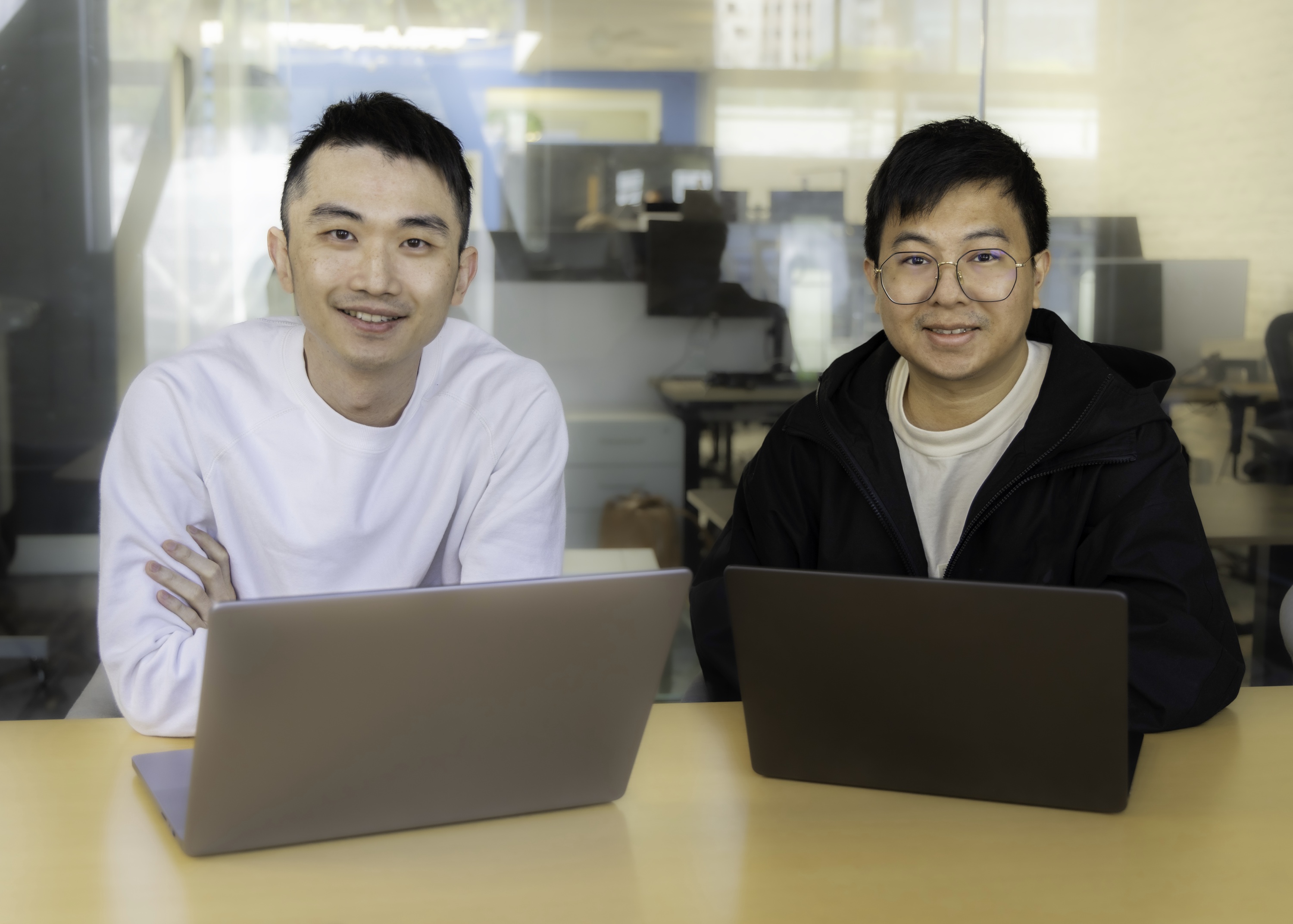 HeyGen co-founders seated behind their laptops in an office