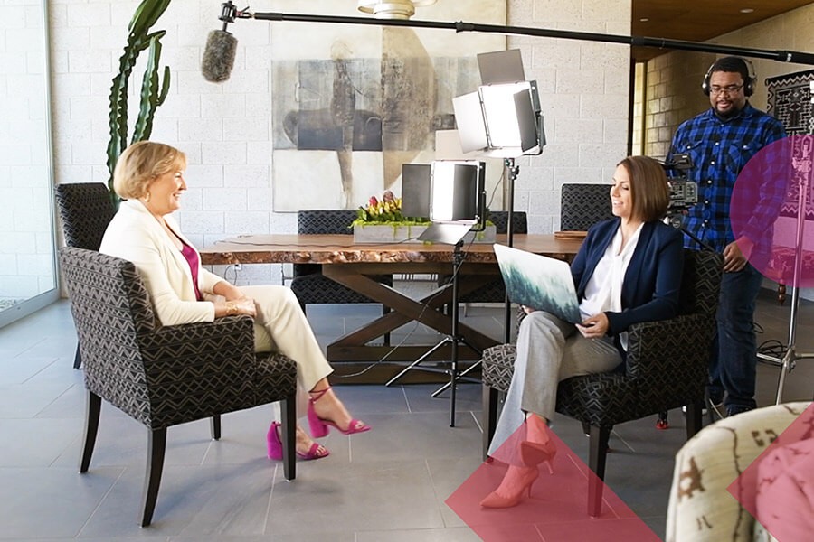 Joyce Mullen, seated at left, talks with Jillian Viner while a camera crew records their interview.
