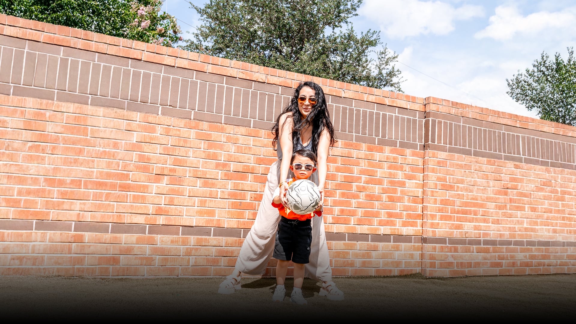 A parent and young child pose with a soccer ball