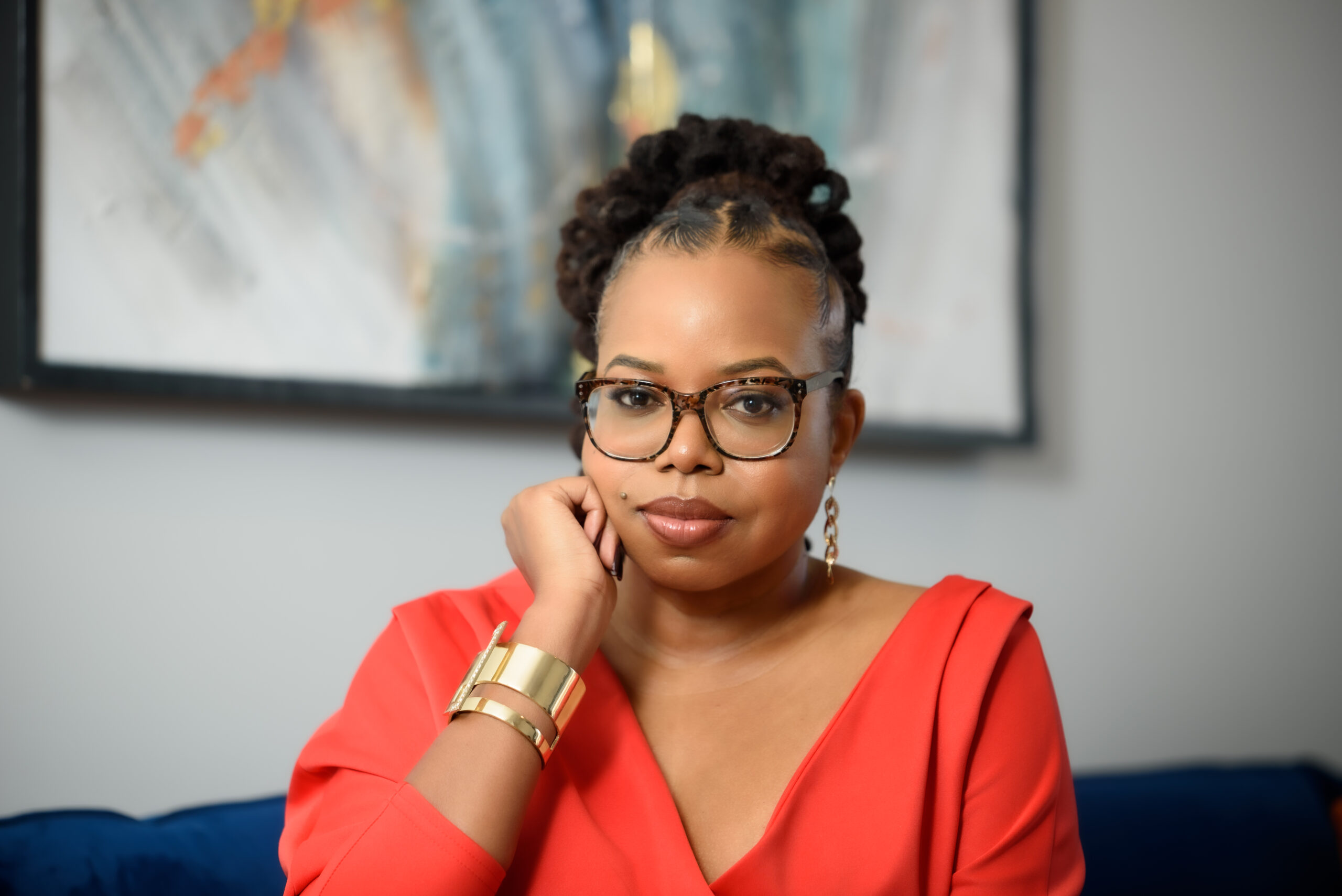 JSW Media Group founder Jameka S. Whitten seated in front of abstract artwork