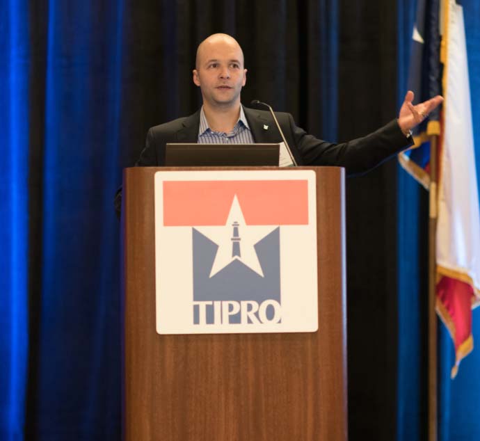Jud Walker speaking at a TIPRO lectern with his arm extended