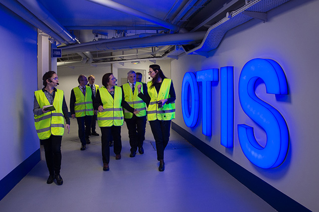 Judy Marks, center, walks with Otis employees wearing high-visibility vests