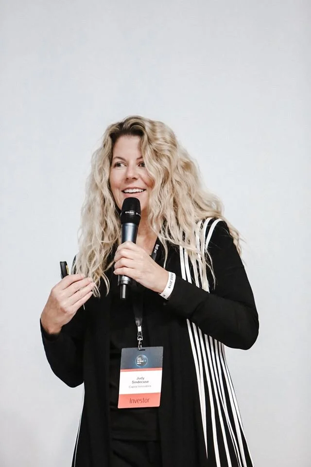 Judy Sindecuse speaking into a microphone while holding a presentation remote