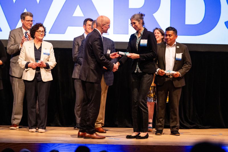 Julia Terenjuk receives her alumni award from Bloch School dean Brian Klaas on stage at UMKC.