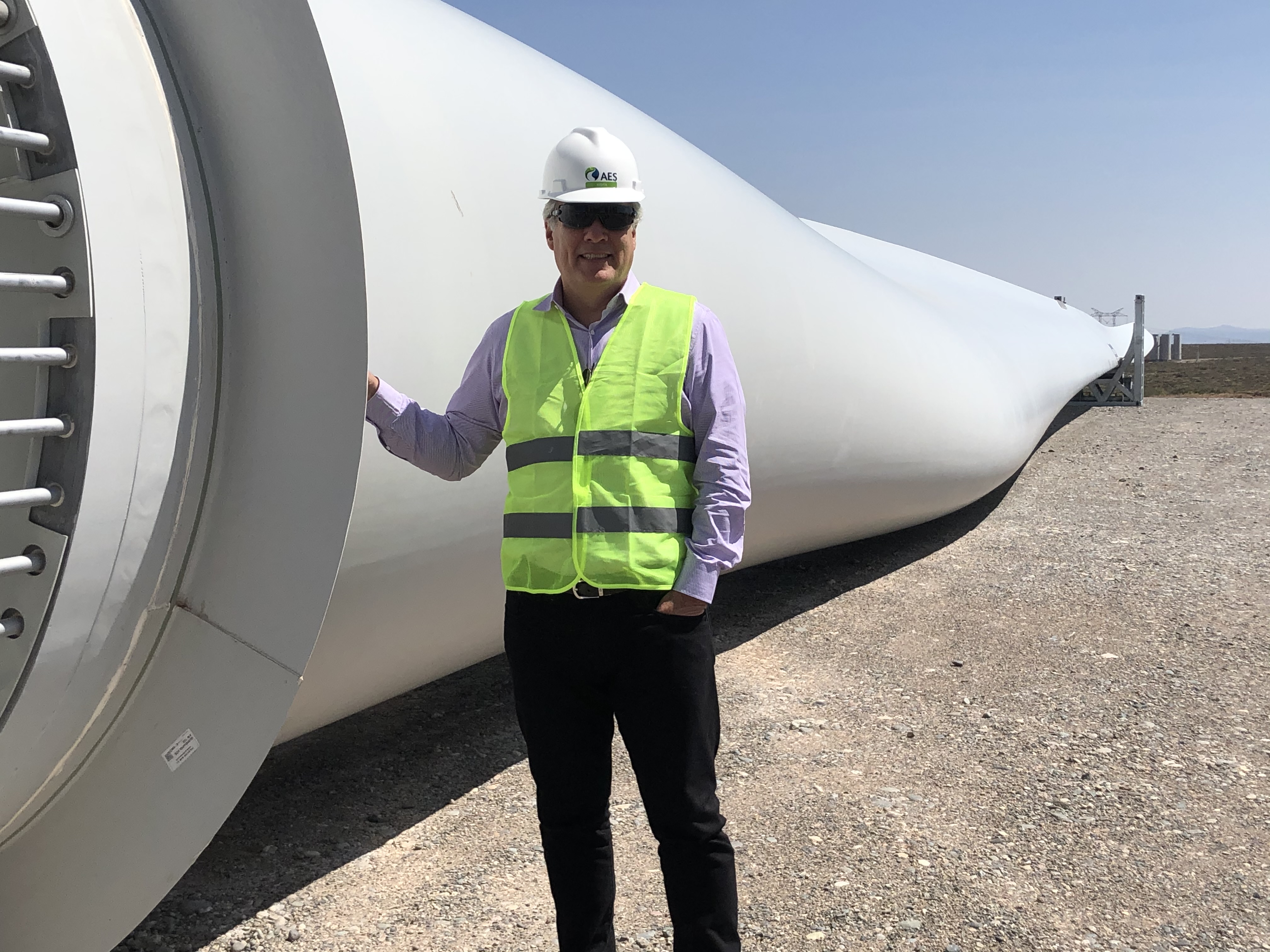 Julian Nebreda in an AES hard hat and high-visibility vest beside a wind-turbine blade