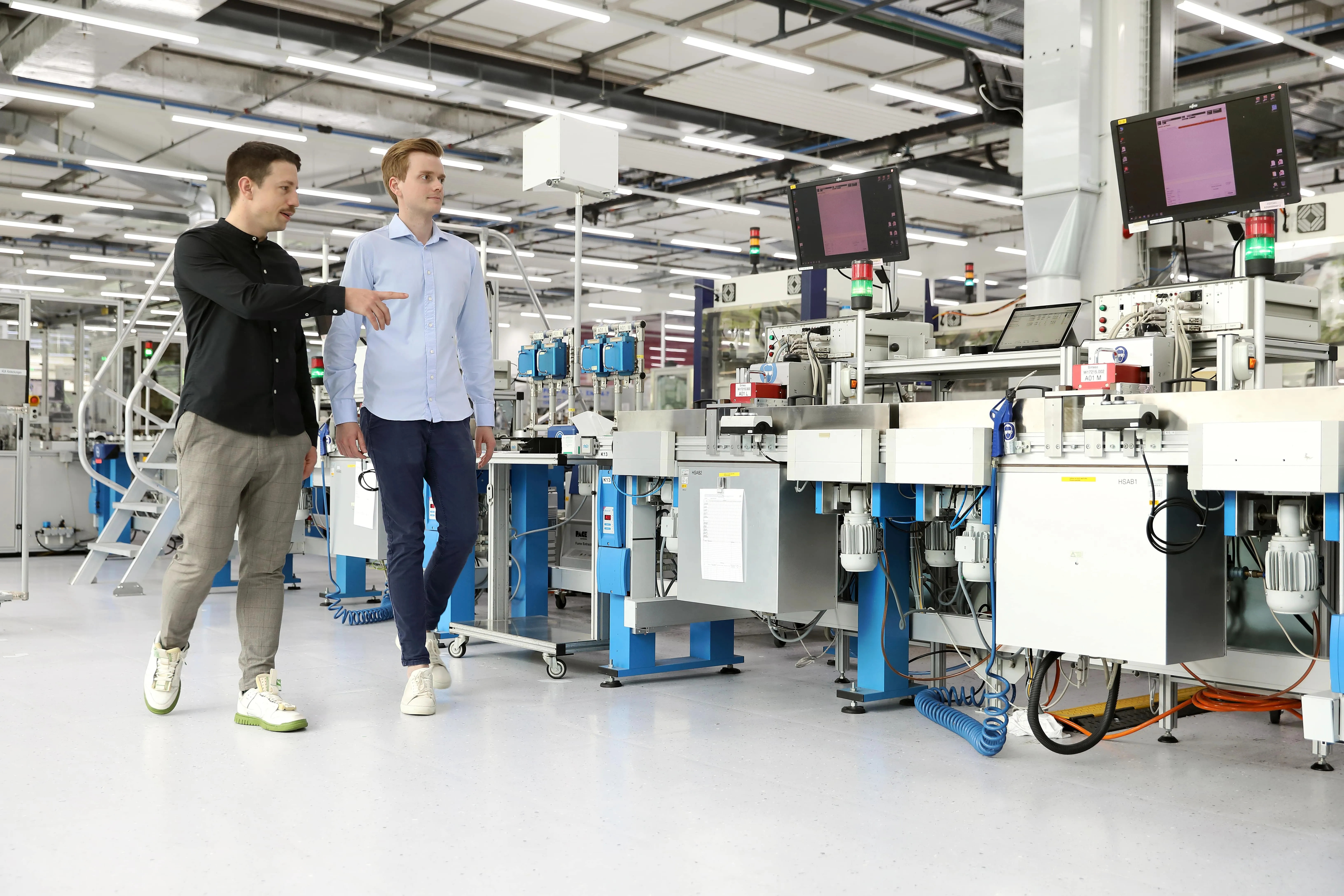Bernhard Kratzwald and Julian Senoner walking beside machinery at a Siemens factory in Zug