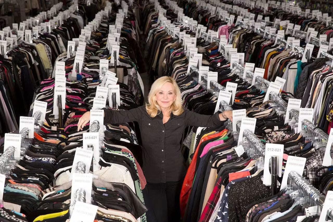 Julie Wainwright stands among densely packed racks of labeled clothing at The RealReal