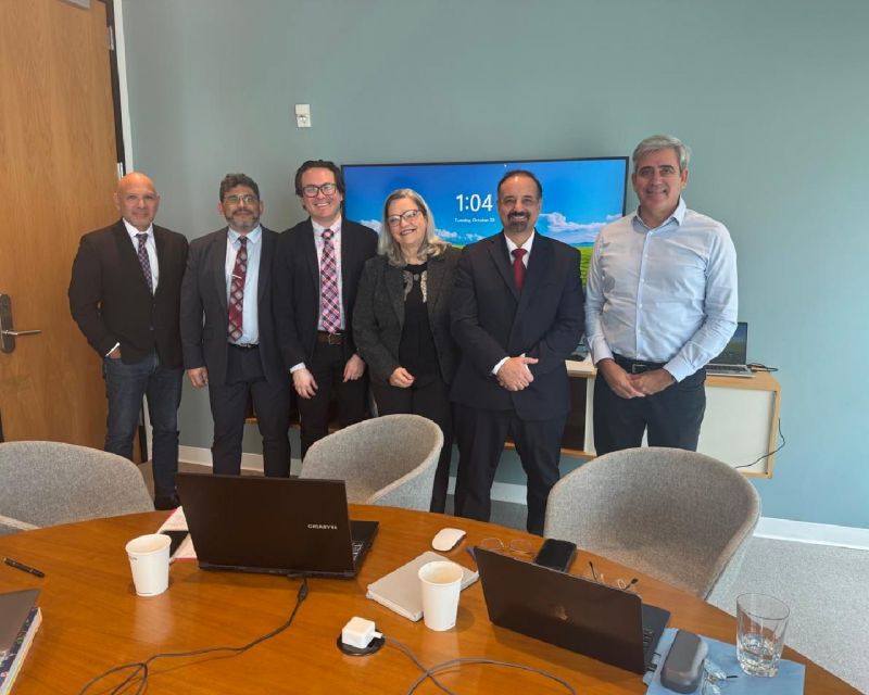 Six participants standing behind a conference table in the group photograph Julio Ardiles shared with his university collaboration post