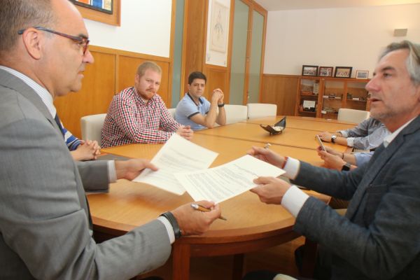 Julio Sánchez and university representatives reviewing documents around a meeting table